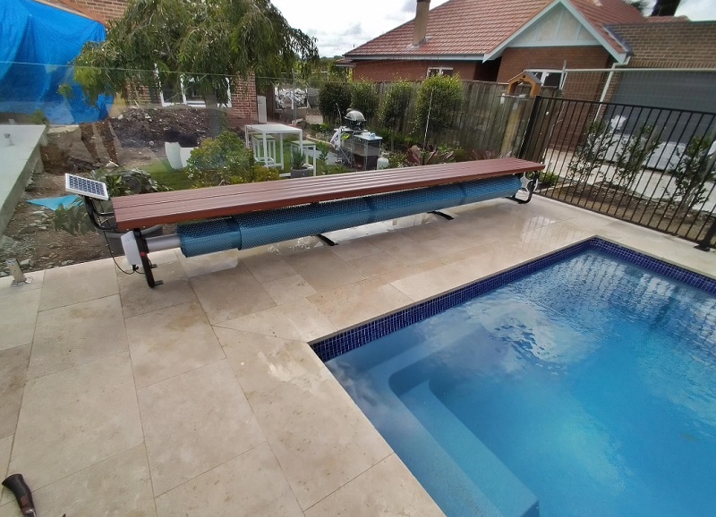 Pool cover and blanket roller setup beside a residential pool